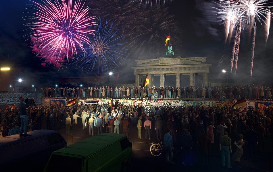 Menschen feiern mit Feuerwerk am Brandenburger Tor den Mauerfall in Berlin.
