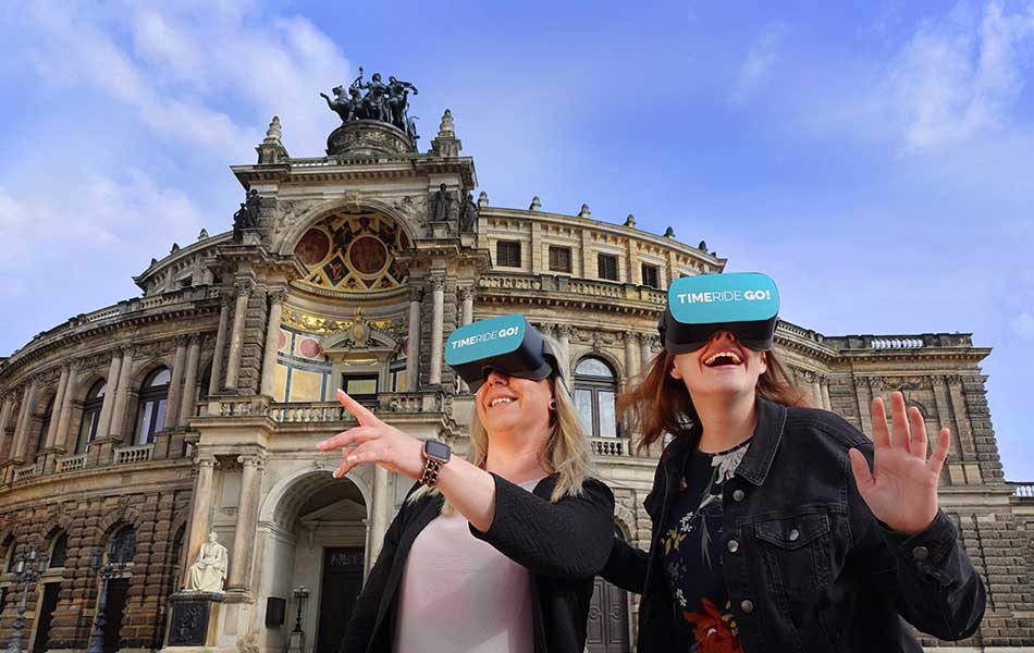 Frauen mit VR-Brillen vor historischem Gebäude lächeln und gestikulieren.