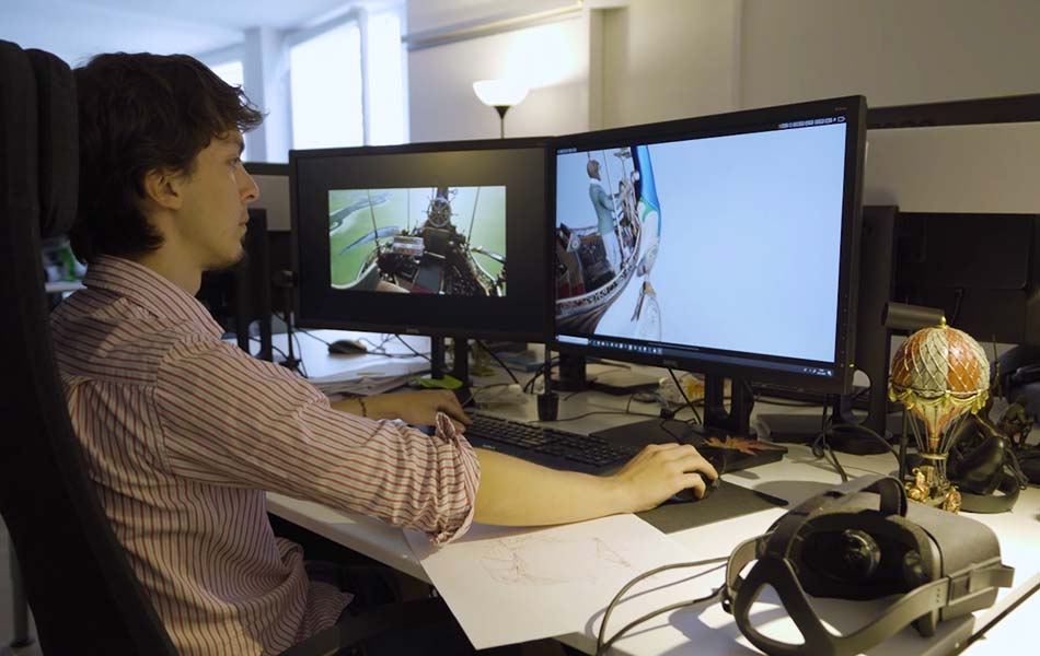 Mann programmiert VR-Inhalte an zwei Bildschirmen in einem Büro